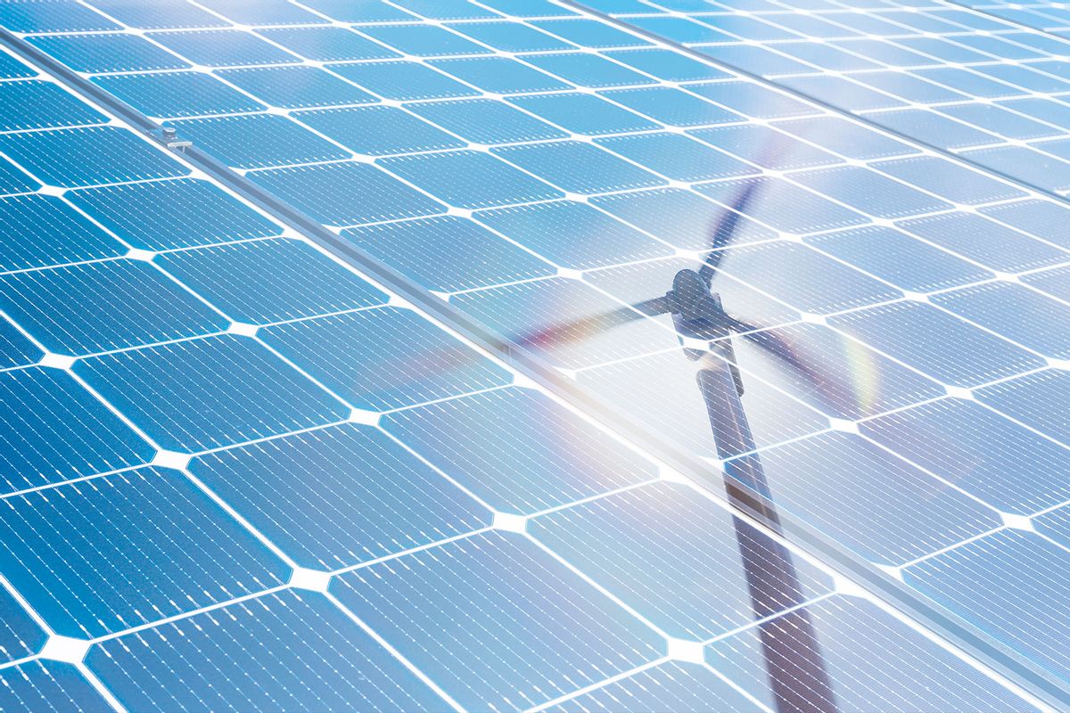 Wind turbine reflected in solar panels (Getty Images/Tetra Images)
